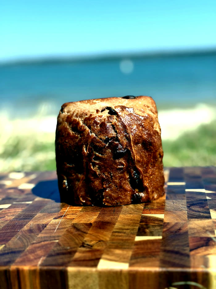A single loaf on a board against the grass and the water